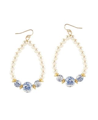 Pearl teardrop earrings with gold and porcelain detailing at the bottom.