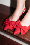 red soft faux suede kitten heel with a pointed toe and delicate bow, adjustable buckle strap