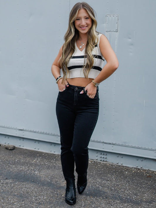 cream and black stripe v neck sleeveless cropped sweater vest with black high waisted boyfriend jeans and black pointed toe booties