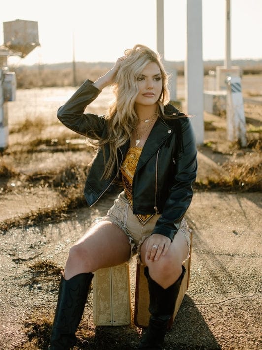 black faux leather fringe long sleeve jacket with golden yellow satin bandana sleeveless crop top and taupe high waisted rhinestone fringe denim shorts
