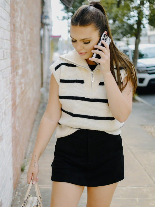 white and black striped knit quarter zip sleeveless sweater vest with black suede mini skort