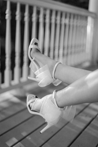 white sparkling, shimmery heels with a square toe design and a delicate ankle strap with unique bow back detail, back view