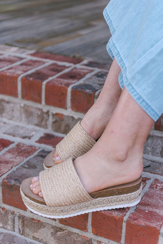 Sandals with a woven design and a rounded toe, slip on style and a platform sole for added height, side view