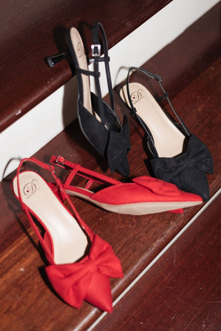 sleek black design and trendy pointed toe kitten heels with a bow and adjustable back strap with buckle, heel view