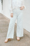 White wide leg jeans with blue floral detailing and raw hem.