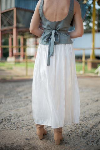 Person wearing a brown top and white skirt with a blurred background