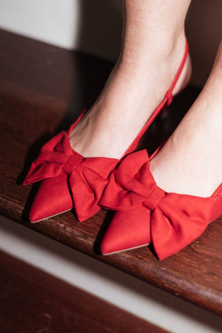 red soft faux suede kitten heel with a pointed toe and delicate bow, adjustable buckle strap