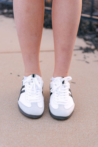 White and black low top sneaker with black and grey details, front view