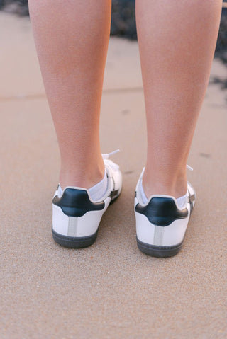 White and black low top sneaker with black and grey detail, back view